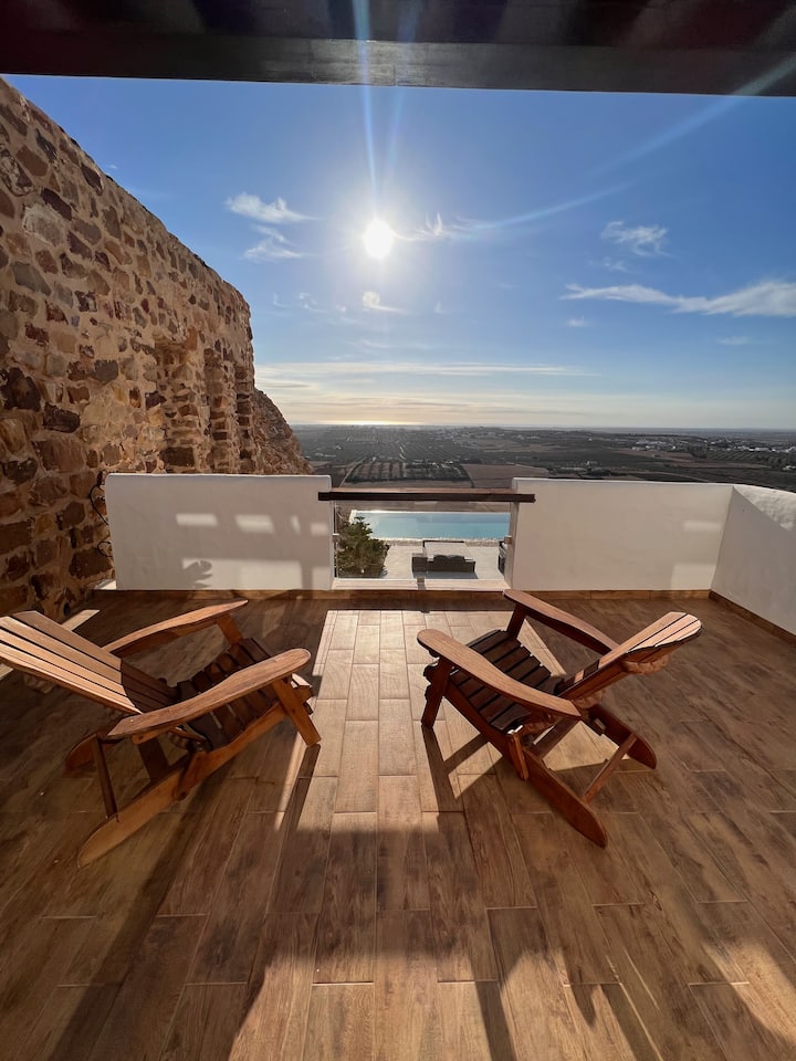 Terrasse en bois d'une suite, deux transats face au soleil et à la piscine.